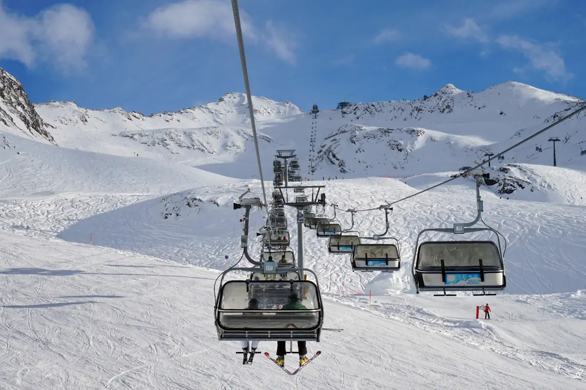 A chairlift climbing above a snowy alpine piste